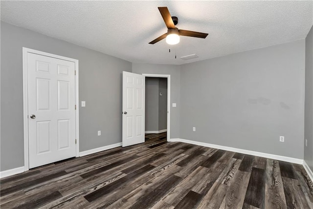 unfurnished bedroom with baseboards, a ceiling fan, dark wood finished floors, and a textured ceiling