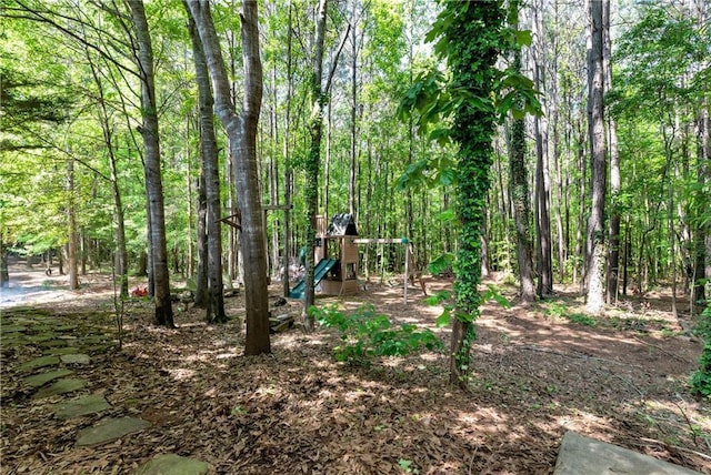view of yard featuring a playground and a forest view