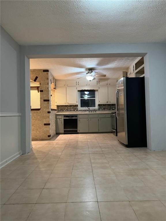 kitchen featuring black dishwasher, decorative backsplash, white cabinetry, and light tile patterned flooring