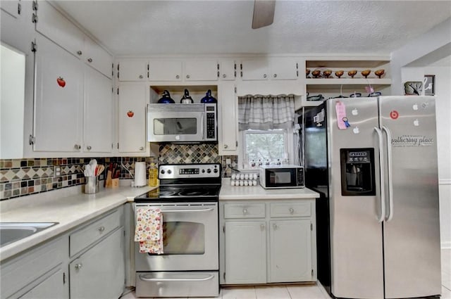 kitchen with appliances with stainless steel finishes, tasteful backsplash, white cabinetry, ceiling fan, and light tile patterned flooring