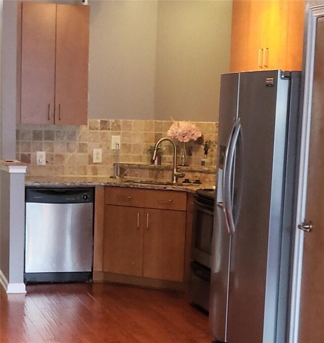 kitchen featuring decorative backsplash, appliances with stainless steel finishes, dark wood-type flooring, and sink