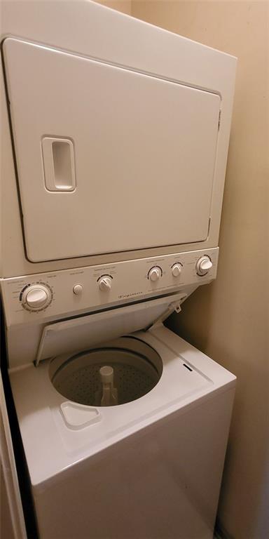 clothes washing area with stacked washing maching and dryer