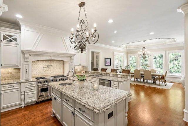 kitchen with hanging light fixtures, a kitchen island with sink, sink, and stainless steel appliances