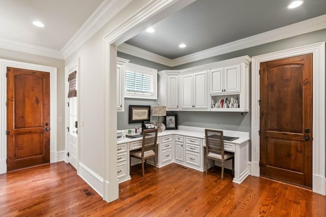 office area with dark hardwood / wood-style floors, built in desk, and crown molding