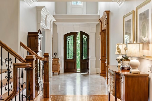 foyer entrance with ornate columns, ornamental molding, and french doors