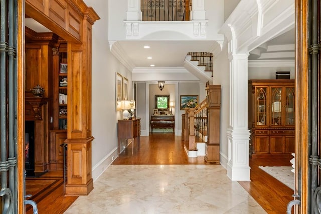 foyer entrance with decorative columns and ornamental molding