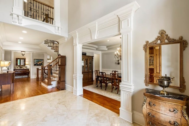 foyer featuring hardwood / wood-style flooring, ornate columns, and crown molding