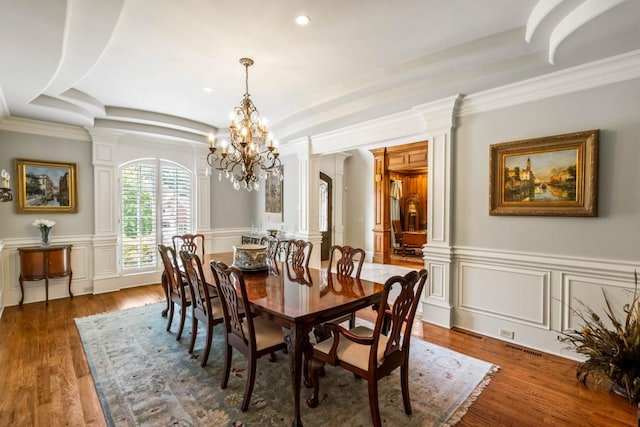 dining space with decorative columns, ornamental molding, dark hardwood / wood-style floors, and a notable chandelier