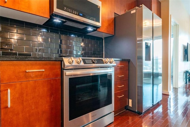 kitchen featuring dark stone countertops, backsplash, stainless steel appliances, and dark hardwood / wood-style floors