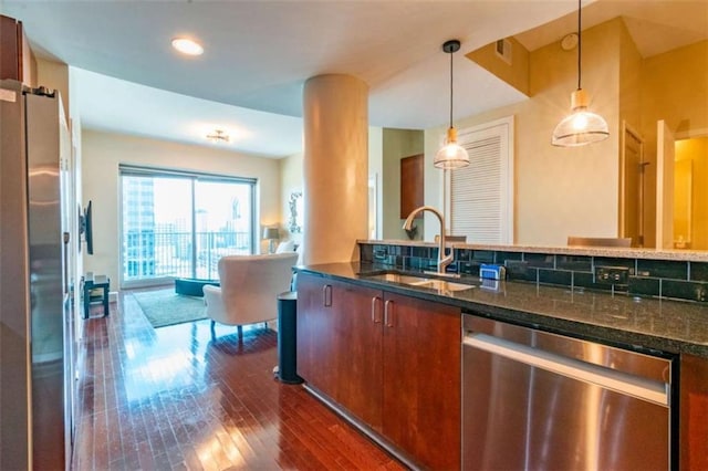 kitchen with sink, hanging light fixtures, appliances with stainless steel finishes, dark hardwood / wood-style floors, and dark stone counters