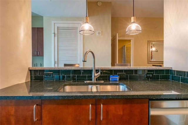 kitchen featuring sink, decorative light fixtures, stainless steel dishwasher, and dark stone counters