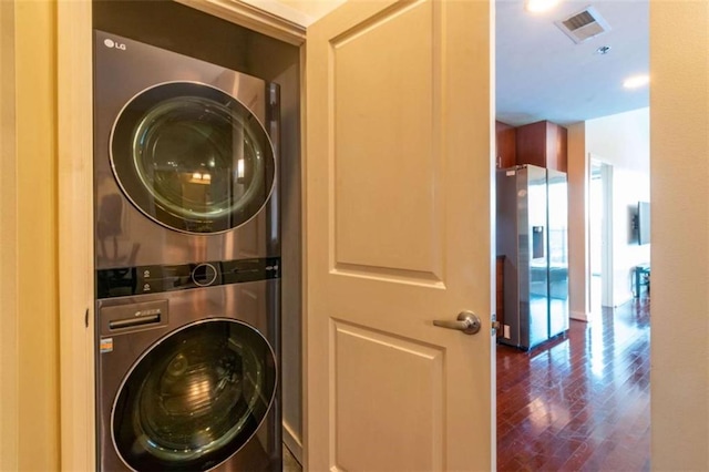 washroom with stacked washer and dryer and dark wood-type flooring