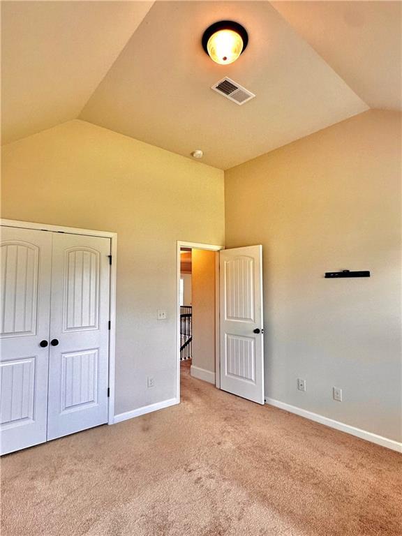 520 Harmony Way, Locust Grove, GA 30248 - unfurnished bedroom with lofted ceiling, carpet, baseboards, and a closet