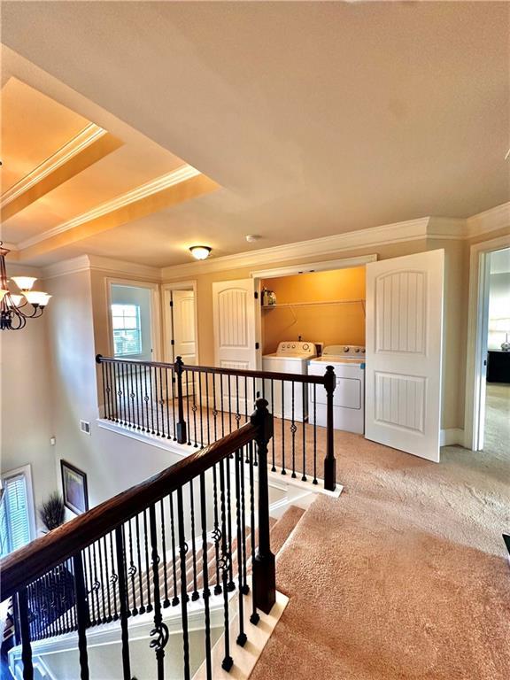 520 Harmony Way, Locust Grove, GA 30248 - hallway featuring independent washer and dryer, an upstairs landing, carpet, ornamental molding, and a chandelier