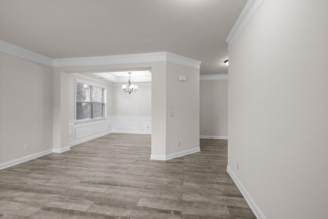 empty room with hardwood / wood-style floors, a notable chandelier, and ornamental molding