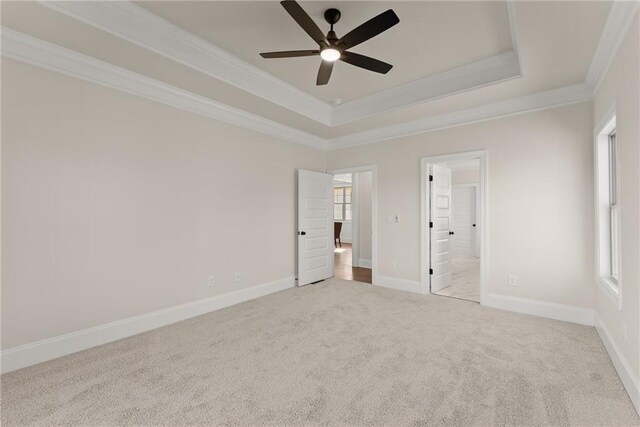 unfurnished bedroom featuring a tray ceiling, ensuite bathroom, crown molding, and ceiling fan