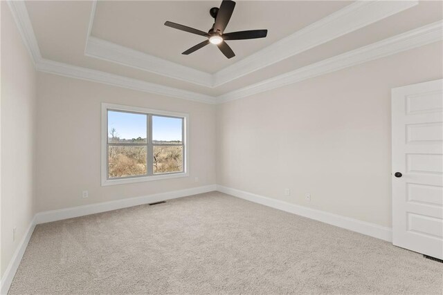 carpeted empty room featuring ceiling fan, a tray ceiling, and ornamental molding