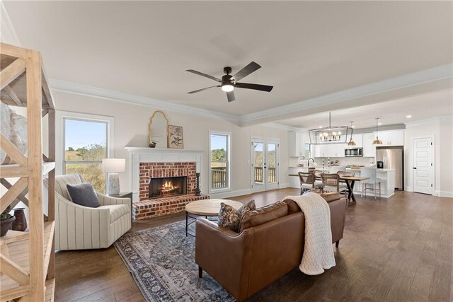 living room with a brick fireplace, ornamental molding, dark hardwood / wood-style flooring, and ceiling fan