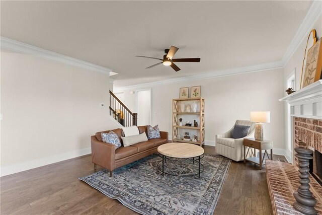 living room featuring ceiling fan, a fireplace, a wealth of natural light, crown molding, and dark wood-type flooring