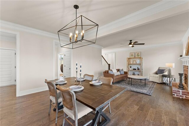 dining area with crown molding, a brick fireplace, ceiling fan with notable chandelier, and dark wood-type flooring