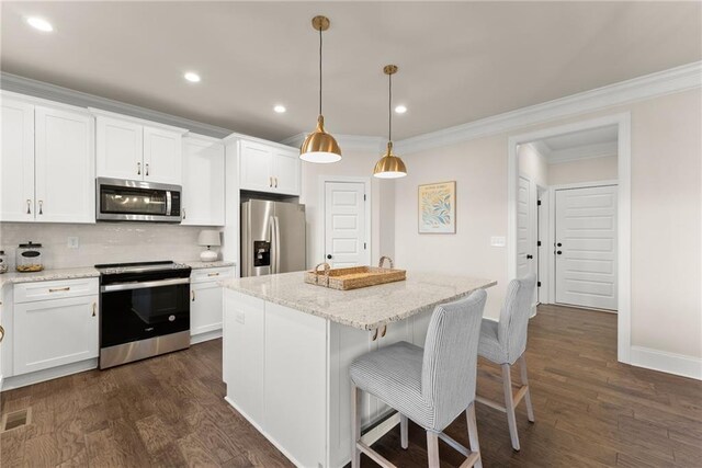 kitchen featuring decorative light fixtures, white cabinetry, a center island, and stainless steel appliances