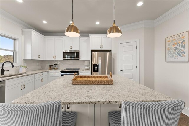 kitchen featuring pendant lighting, a center island, sink, stainless steel appliances, and white cabinets