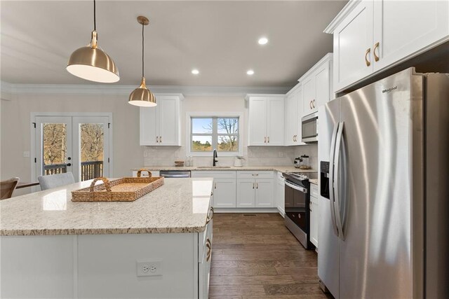 kitchen with a kitchen island, hanging light fixtures, appliances with stainless steel finishes, light stone countertops, and french doors