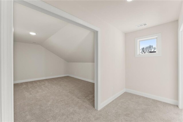 bonus room with light colored carpet and lofted ceiling