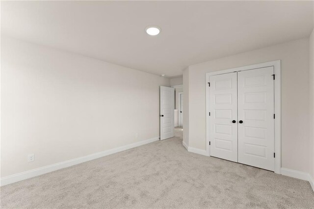 unfurnished bedroom featuring light carpet and a closet