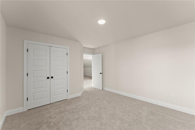 unfurnished bedroom featuring light colored carpet and a closet