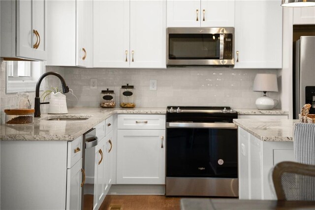 kitchen with appliances with stainless steel finishes, white cabinets, tasteful backsplash, and sink