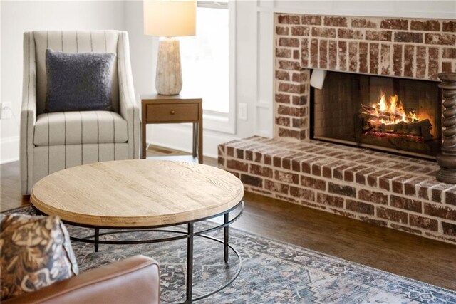 living area with a brick fireplace and hardwood / wood-style flooring