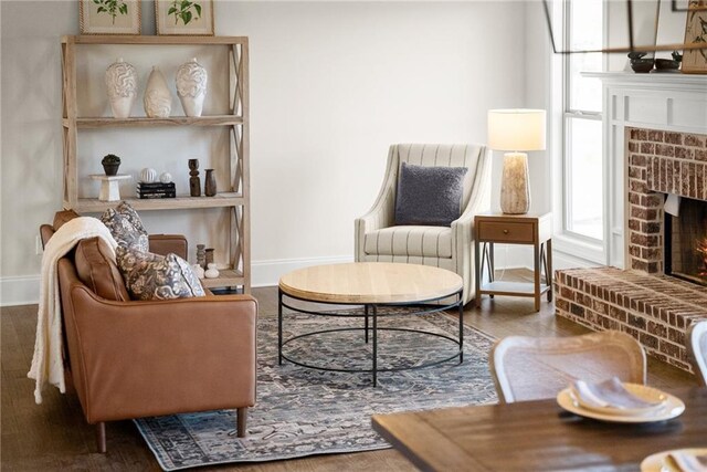 living area with a brick fireplace and hardwood / wood-style floors