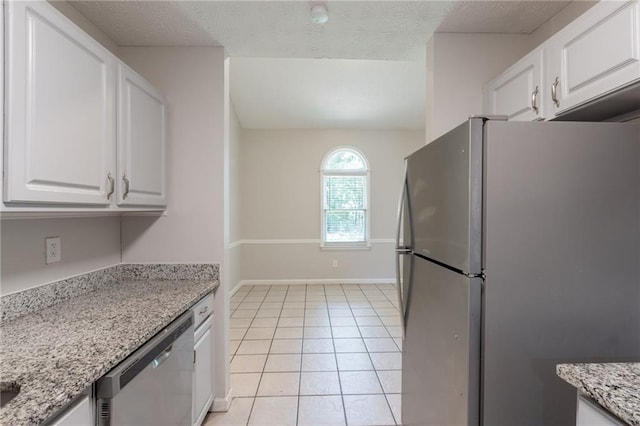 1406 Windy Ridge Ct SE, Conyers, GA 30013 - kitchen with appliances with stainless steel finishes, white cabinetry, light tile patterned floors, baseboards, and light stone counters