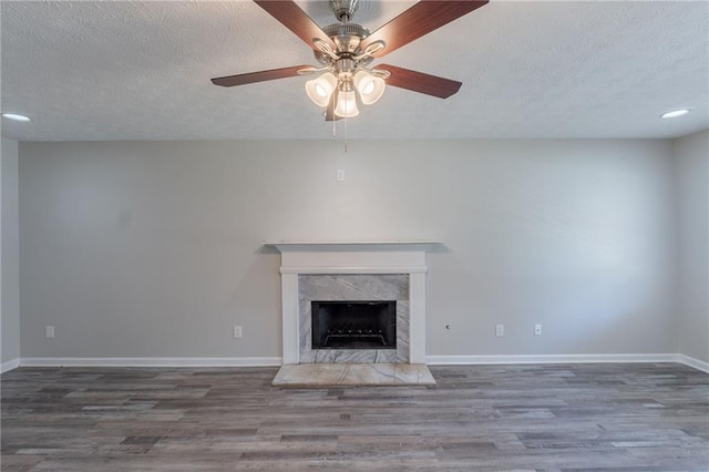 1406 Windy Ridge Ct SE, Conyers, GA 30013 - unfurnished living room with a textured ceiling, wood finished floors, baseboards, a fireplace, and a ceiling fan