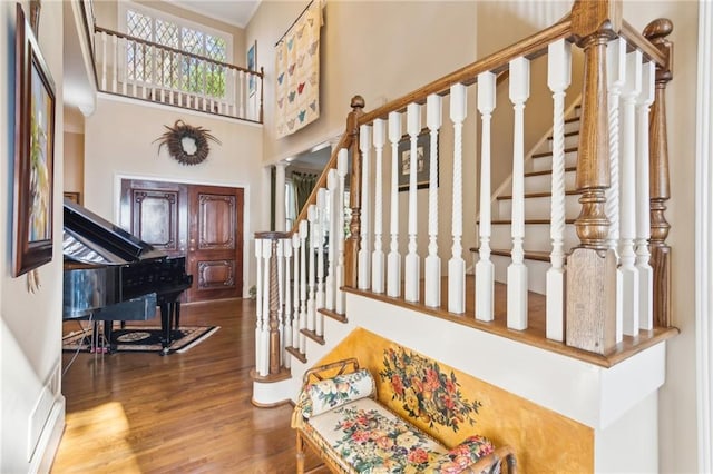 entryway with a towering ceiling, decorative columns, stairway, and wood finished floors