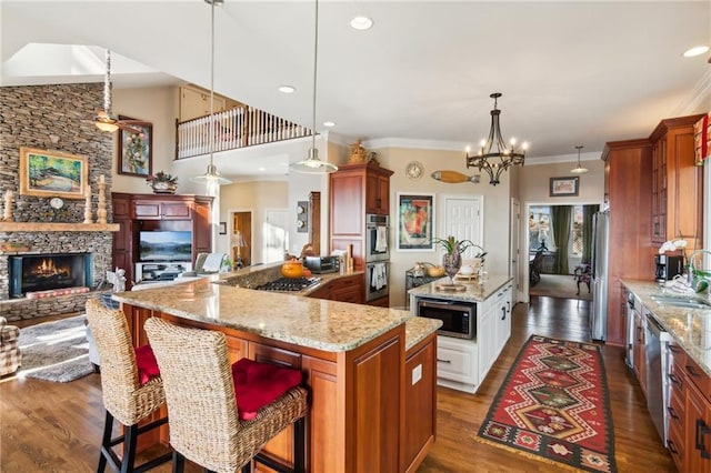 kitchen with stainless steel appliances, a sink, open floor plan, a kitchen bar, and pendant lighting