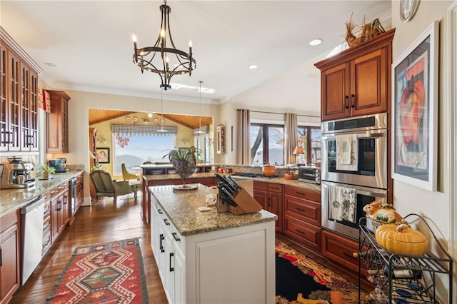 kitchen with light stone counters, decorative light fixtures, stainless steel appliances, white cabinetry, and glass insert cabinets