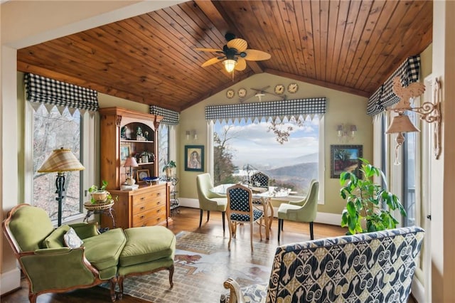 living area with baseboards, a ceiling fan, lofted ceiling, wood ceiling, and light wood-type flooring