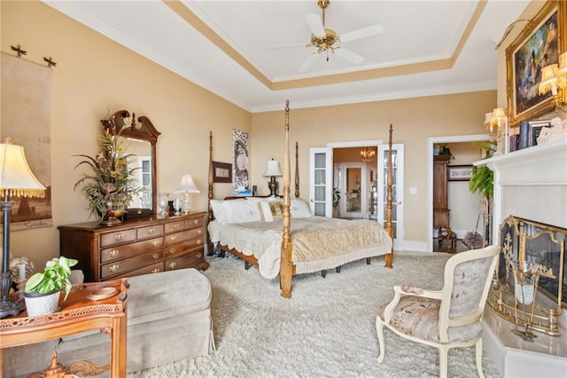 bedroom featuring carpet floors, a glass covered fireplace, a raised ceiling, and crown molding