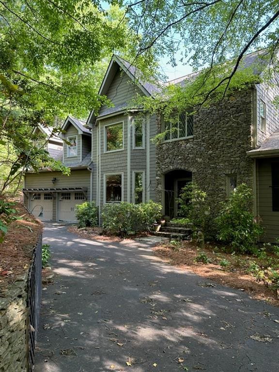 view of front facade with a garage, driveway, and stone siding