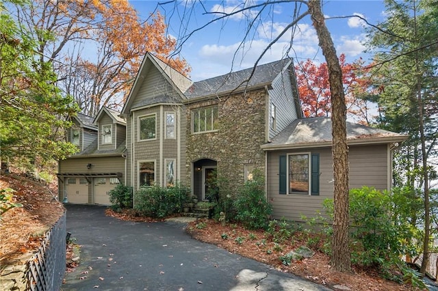 view of front of property with stone siding, an attached garage, and driveway