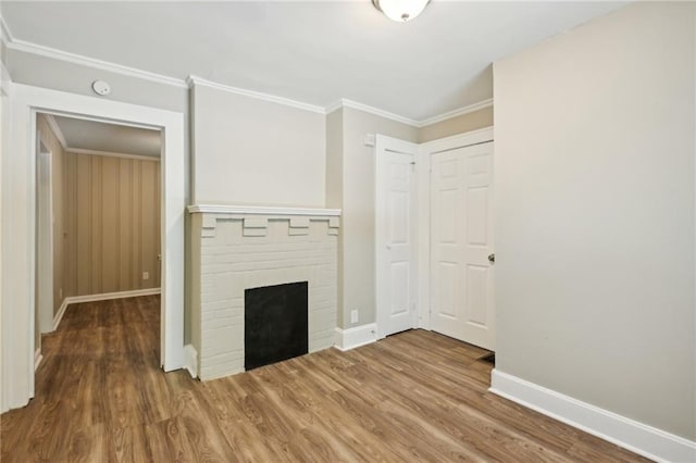 unfurnished living room featuring wood-type flooring, a brick fireplace, and ornamental molding