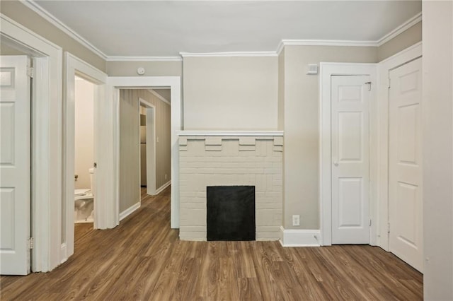 unfurnished living room featuring ornamental molding, dark hardwood / wood-style flooring, and a brick fireplace