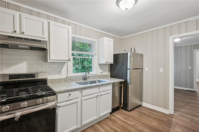 kitchen featuring white cabinetry, light wood-type flooring, light stone countertops, appliances with stainless steel finishes, and sink