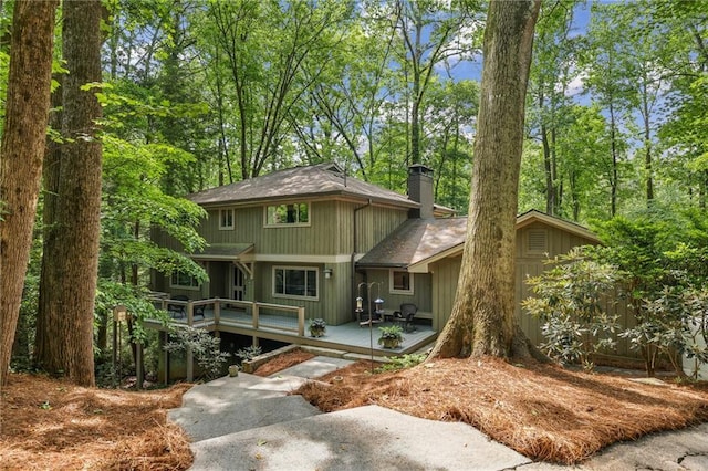 view of front of house featuring a shingled roof, a wooden deck, and a chimney