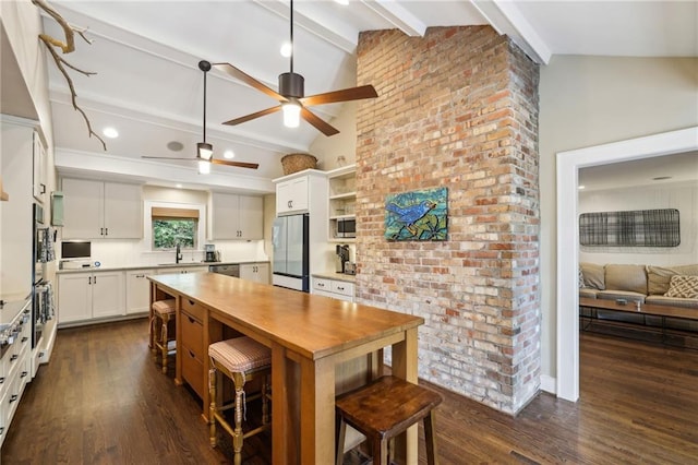 kitchen with ceiling fan, open shelves, appliances with stainless steel finishes, lofted ceiling with beams, and a sink