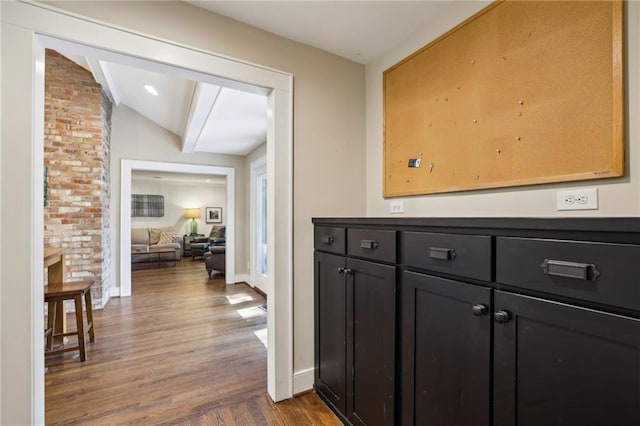 hallway featuring baseboards, dark wood-style floors, and lofted ceiling