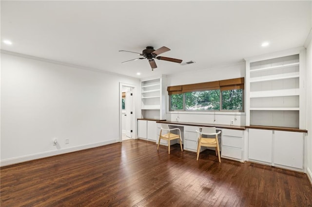 unfurnished office featuring ceiling fan, visible vents, built in shelves, and wood finished floors