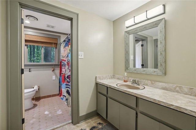 bathroom with vanity, baseboards, visible vents, and toilet